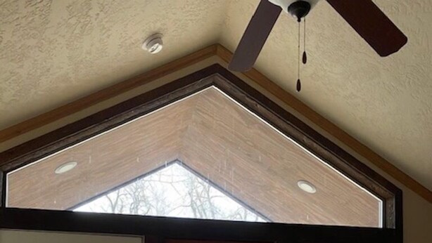 A room with a large sliding glass door leading to a deck, a ceiling fan, and a view of a wooden deck outside.