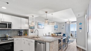 A modern kitchen with white cabinets, stainless steel appliances, and granite countertops.