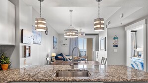 A kitchen with granite countertops, stainless steel appliances, and pendant lighting.