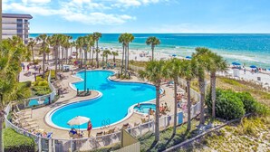 A resort with a large pool, palm trees, and a beach view.