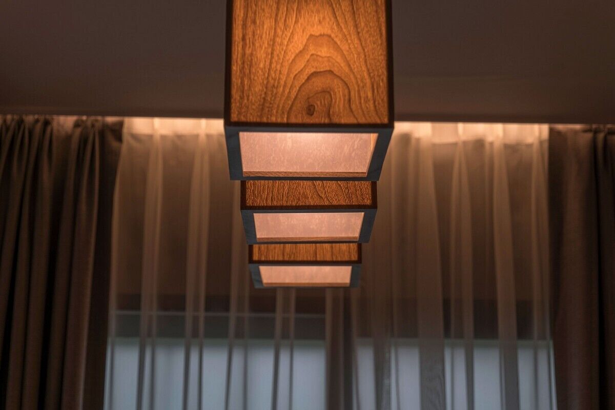 A modern ceiling light fixture with a wooden finish and multiple light panels.