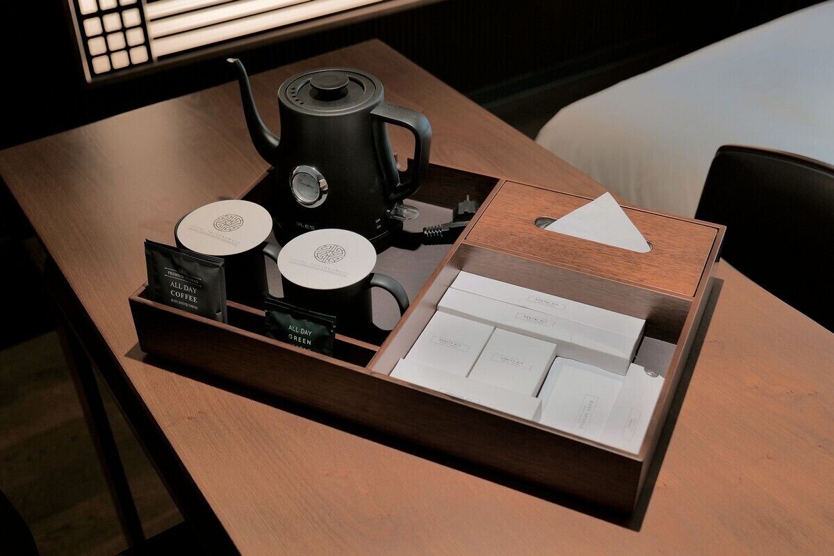 Une table en bois avec une machine à café, deux dosettes de café et un plateau contenant une carte des cafés.