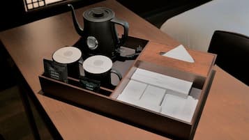 A wooden table with a coffee maker, two coffee pods, and a tray with a coffee menu.