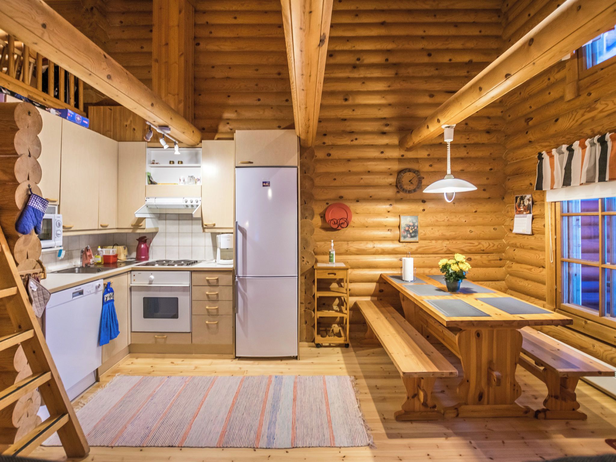 L’intérieur d’une cabane en rondins comprend une cuisine, un coin repas et un banc en bois.