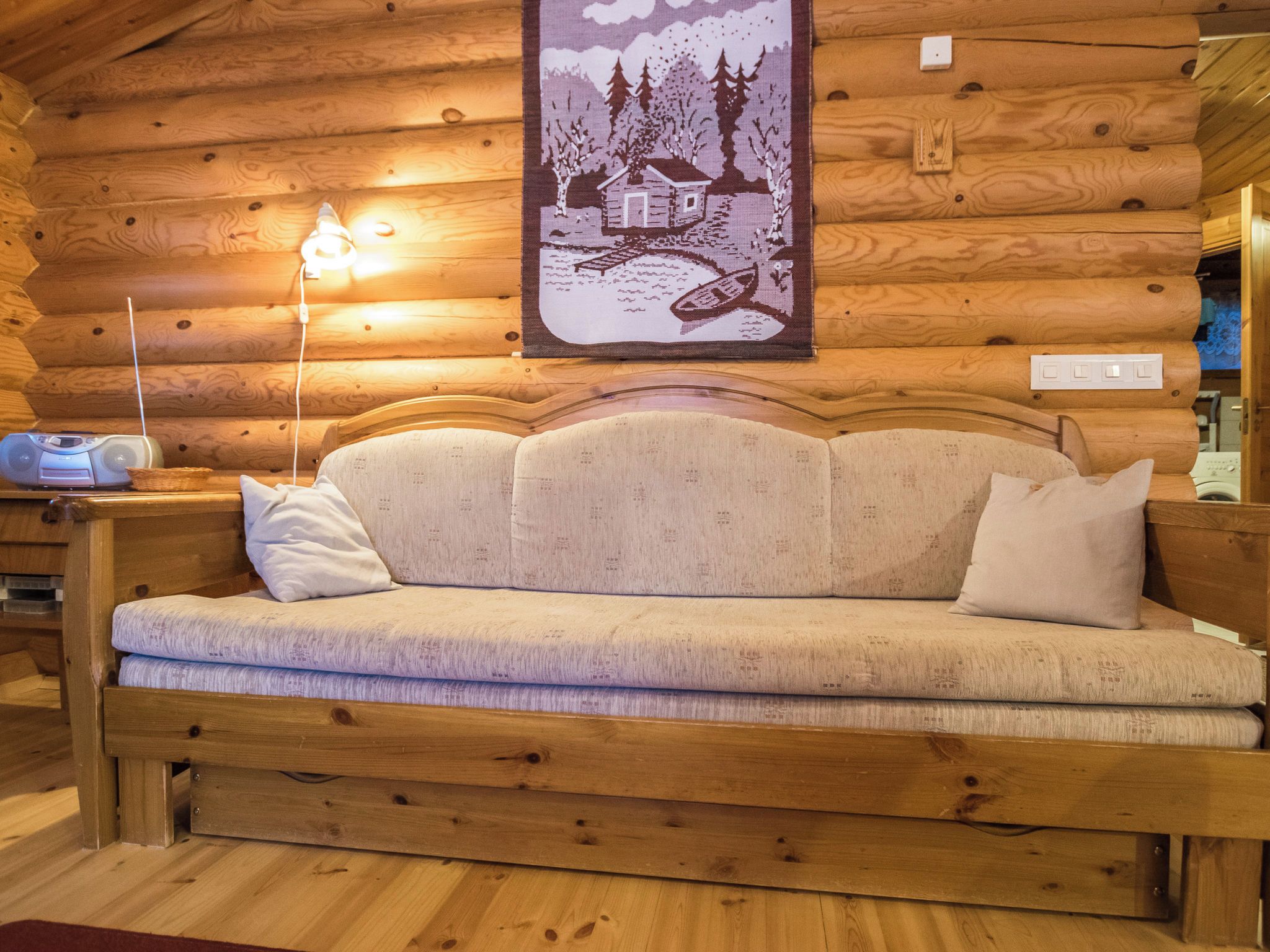 L'intérieur d'une cabane en rondins, avec un canapé, une lampe et une décoration murale.
