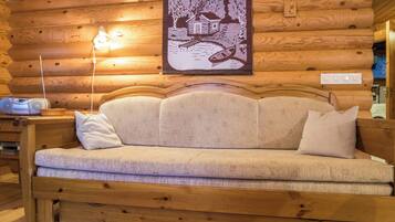 L'intérieur d'une cabane en rondins, avec un canapé, une lampe et une décoration murale.