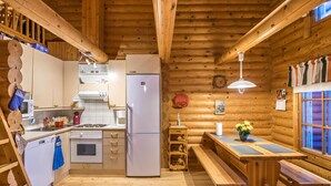 Acogedor interior de cabaña de madera con cocina, comedor y un banco.