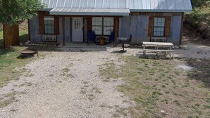 A rustic cabin with a metal roof, a front porch, and a gravel driveway.