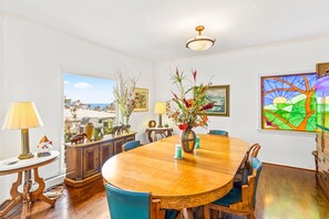 Uma área de refeições com uma mesa e cadeiras de madeira, um vaso com flores e uma janela de vitrais.