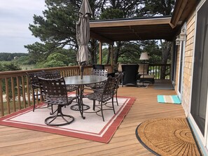 Une terrasse extérieure couverte, avec une table ronde et des chaises, un banc et une lampe.