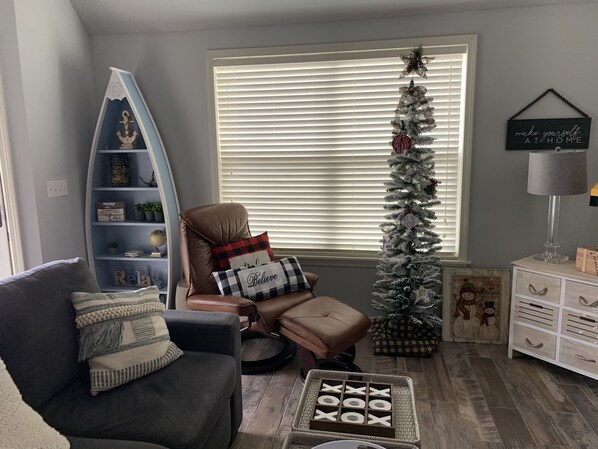 A cozy living room with a dark grey sofa, a small round coffee table, and a Christmas tree. - Blue Cottage Pickwick, Tn (Counce)