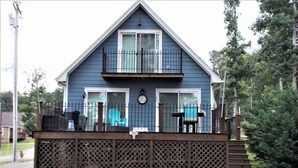 Une maison à deux étages avec un balcon, une clôture en bois et une petite terrasse.