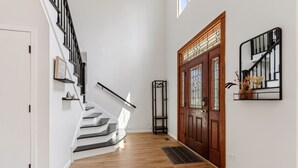 Eine Treppe mit schwarzer Handlauf, die zu einer Holztür mit Glasscheiben führt.