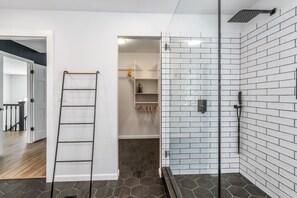 Uma casa de banho moderna com chuveiro, porta de vidro e escada de madeira.