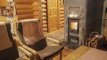 L’intérieur d’un chalet confortable, avec une cheminée, des murs en bois et un coin repas.