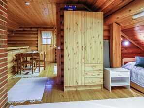 A wooden cabin interior with a bed, a desk, and a wardrobe.