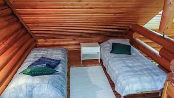 Une petite cabane en bois avec deux lits simples, chacun étant équipé d’un oreiller et d’une couverture.