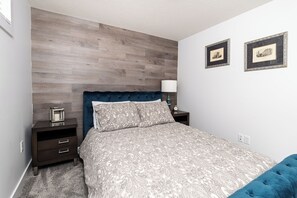 Una camera da letto con un letto, un comodino, una lampada e due quadri appesi al muro.