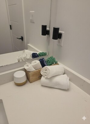 A bathroom with a white sink, a mirror, a towel rack, and a wooden box with towels. - Cozy, modern suite in trendy, historic Hazeldean. Close to Whyte/UofA
(Edmonton)