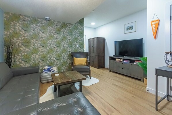 A living room with a sofa, a coffee table, a TV, and a cabinet. - Cozy, modern suite in trendy, historic Hazeldean. Close to Whyte/UofA
(Edmonton)