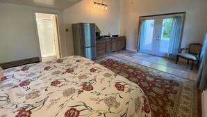 A bedroom with a bed, a ceiling fan, a kitchenette, and a sliding glass door leading to a balcony.