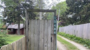 A wooden gate with a number sign, a gravel path, and a wooden fence.