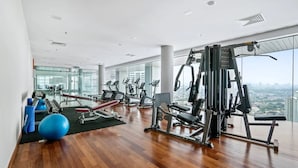A spacious gym with various exercise equipment, large windows offering city views, and a polished wooden floor. - Deluxe2 Paradigm Mall (Petaling Jaya)