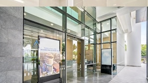 A modern building entrance with glass doors, a large poster advertising residences, and a tiled floor. - Deluxe2 Paradigm Mall (Petaling Jaya)