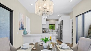 A modern kitchen with white cabinets, a central island, and a chandelier.
