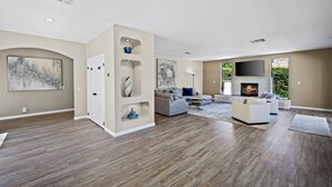 A spacious living room with a fireplace, a large TV, and a modern fireplace mantel.