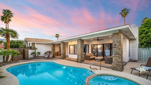 A poolside area with a hot tub, lounge chairs, and a covered patio.
