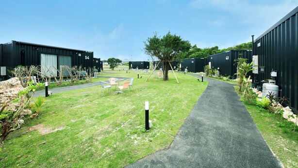 A pathway leading to a grassy area with outdoor seating and a tree. - HOTEL R9 The Yard Miyakojima (Miyakojima)