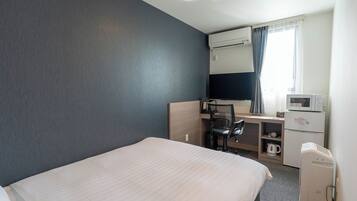 A hotel room with a bed, a desk with a chair, a microwave, a coffee maker, and a TV.
