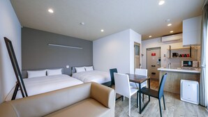 A modern hotel room with two beds, a sofa, a dining table with chairs, and a kitchenette. - HOTEL R9 The Yard Miyakojima (Miyakojima)