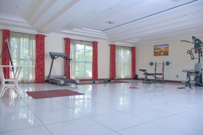 A spacious room with a treadmill, exercise bike, and weight bench. - Homes by Della (Nairobi)
