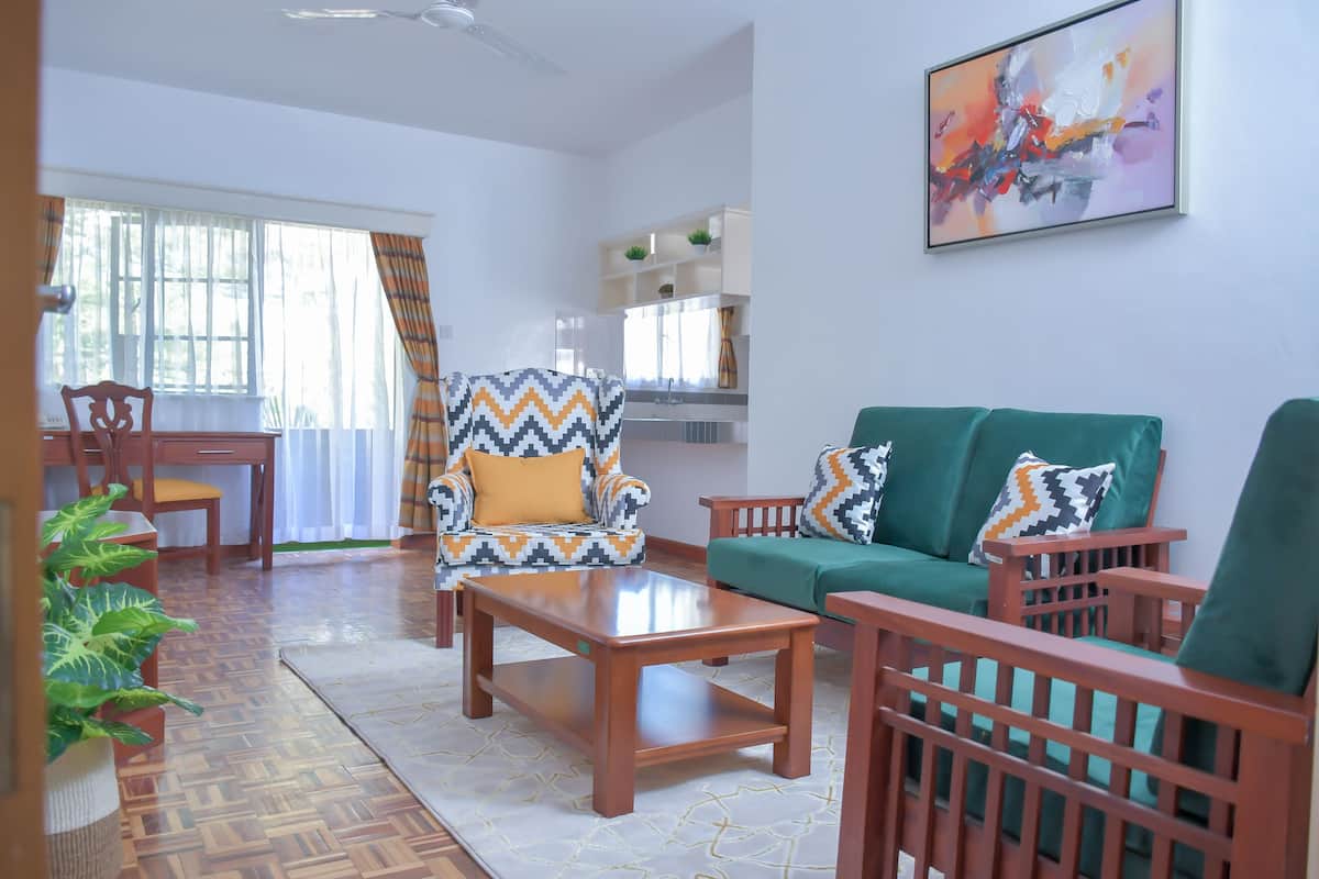 A living room with a wooden coffee table, a green sofa, and a patterned armchair.