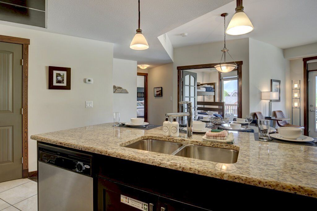 A kitchen with granite countertops, stainless steel appliances, and pendant lighting.