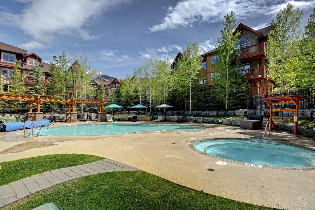 A resort with a large outdoor pool, lounge chairs, and a wooden pergola.