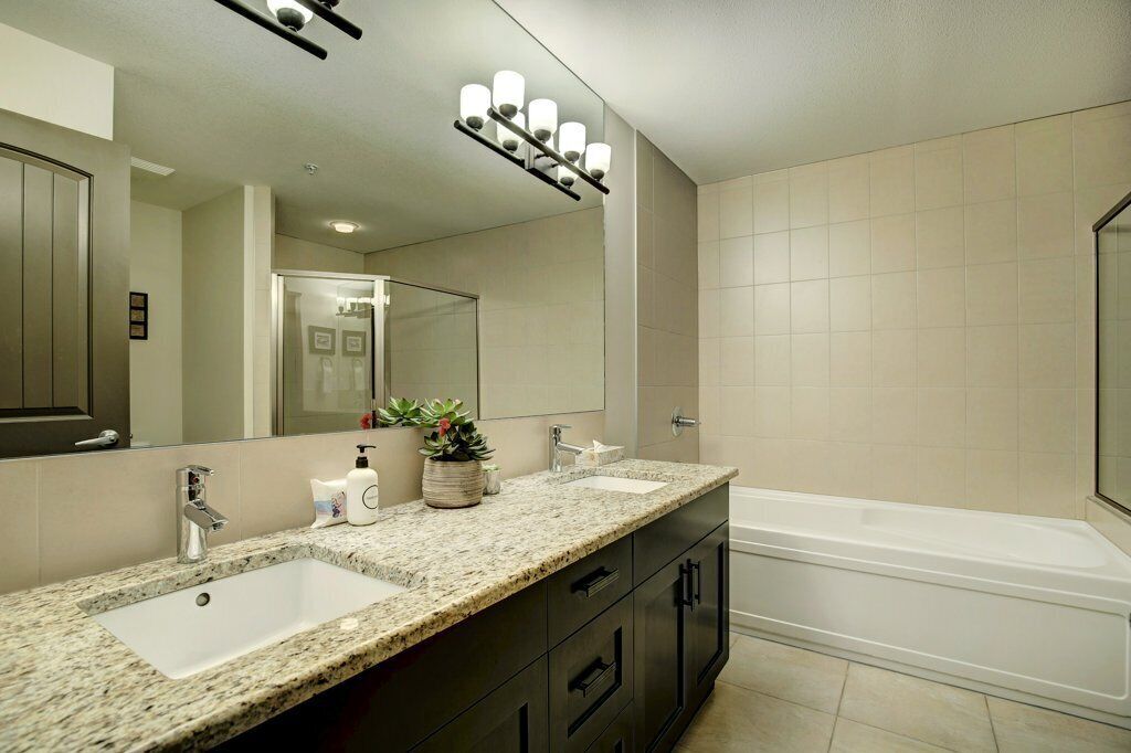 Un baño moderno con lavamanos doble, un espejo grande y una bañera independiente.