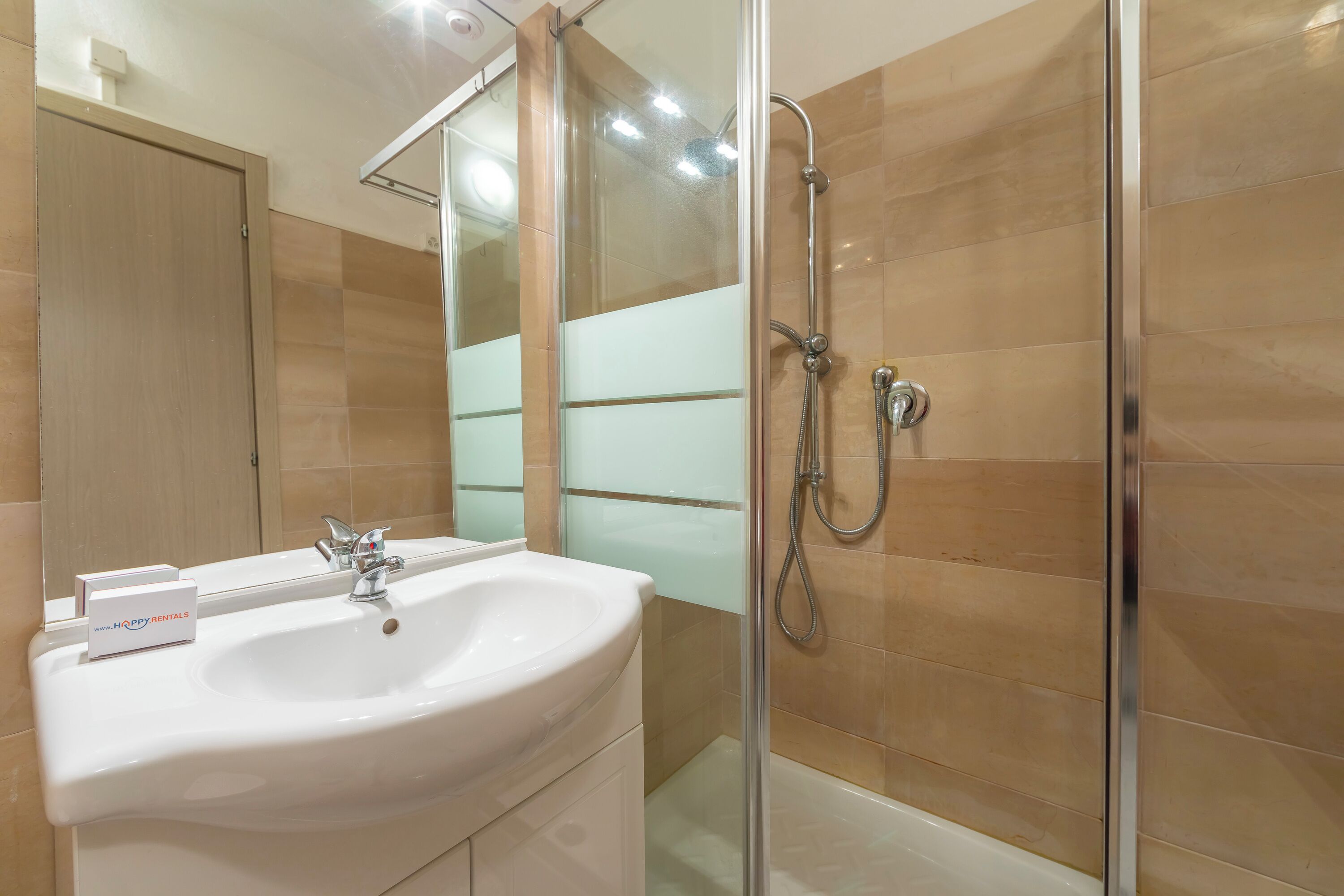 A bathroom with a glass shower enclosure, a sink with a mirror, and a cabinet.