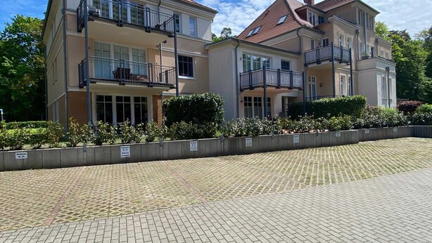 A two-story residential building with balconies, a paved driveway, and a landscaped garden. - Vacation apartment Bucheneck 2 (Graal-Müritz)