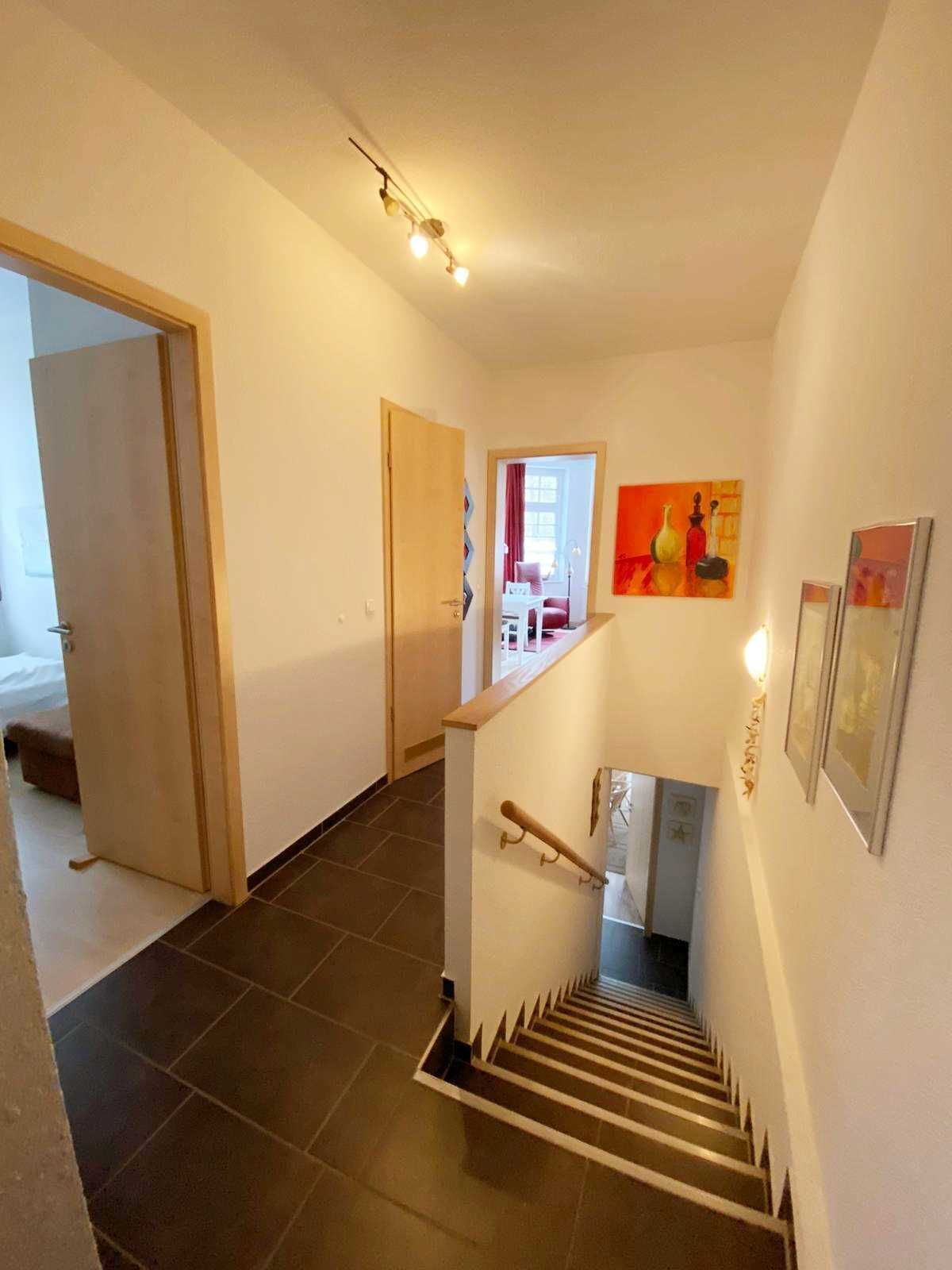 A staircase with a handrail, a door leading to another room, and a painting on the wall.