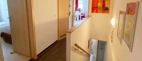 A staircase with a handrail, a door leading to another room, and a painting on the wall.
