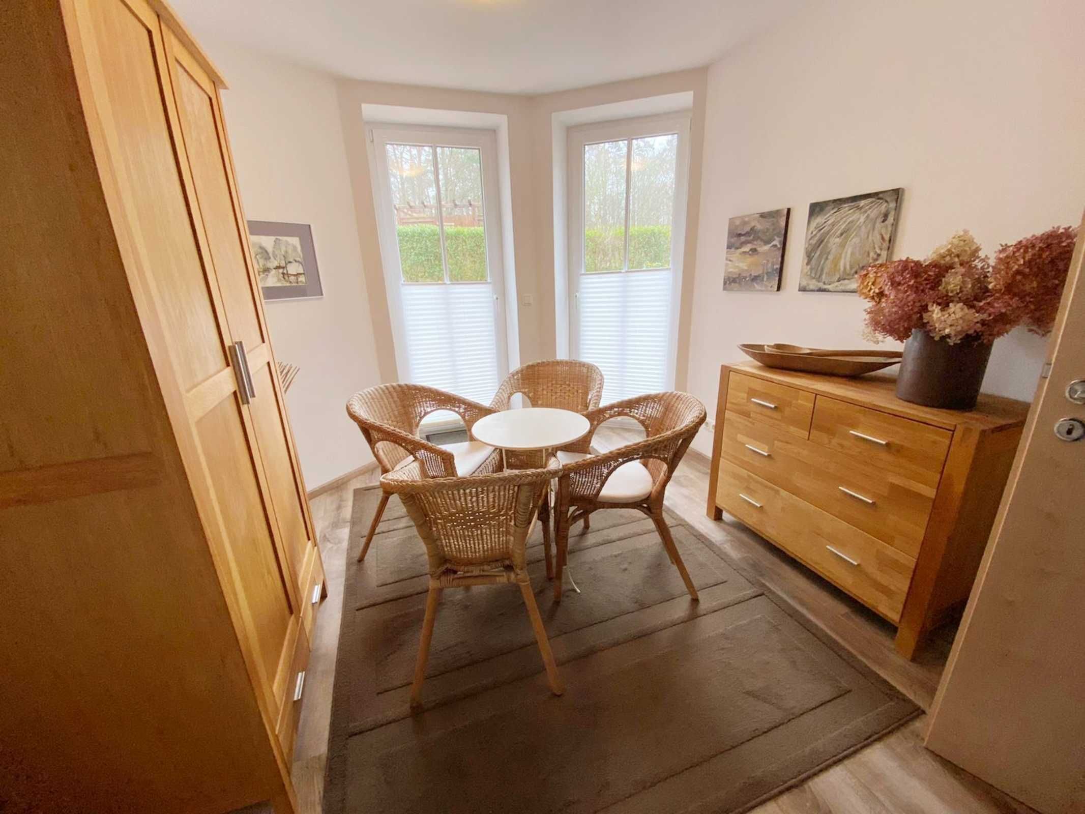 Cocina compacta con zona de comedor, que incluye un mueble de madera, sillas de mimbre y una pequeña mesa.