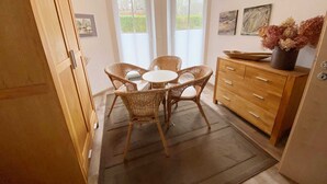A compact kitchen with a dining area, featuring a wooden cabinet, wicker chairs, and a small table. - Vacation apartment Bucheneck 2 (Graal-Müritz)