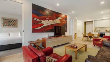 A modern living room with a large painting, a sofa, a coffee table, and a TV.