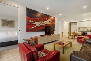 A modern living room with a large painting, a sofa, a coffee table, and a TV.