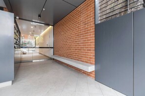 A corridor with a brick wall, a glass door, and a bench.