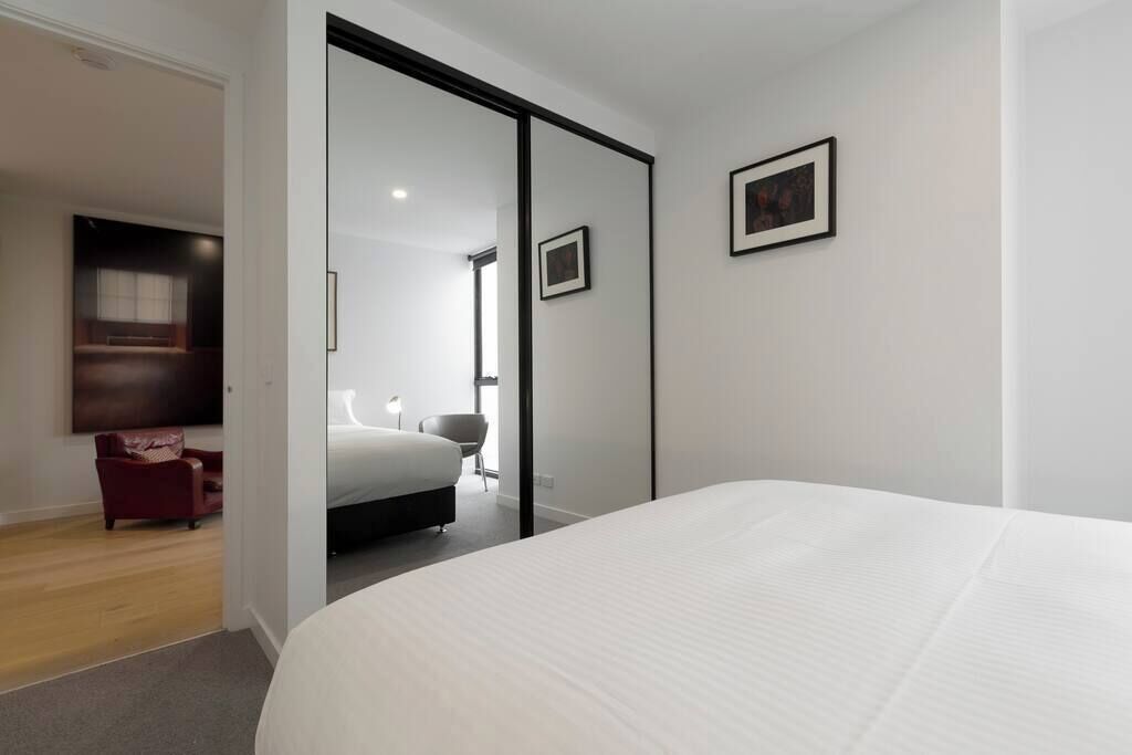Ein modernes Hotelzimmer mit einem großen Bett, einem roten Sessel, einem Schreibtisch und einem Spiegel.