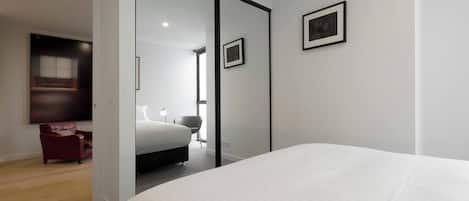 Una habitación de hotel moderna con una cama grande, un sillón rojo, un escritorio y un espejo.